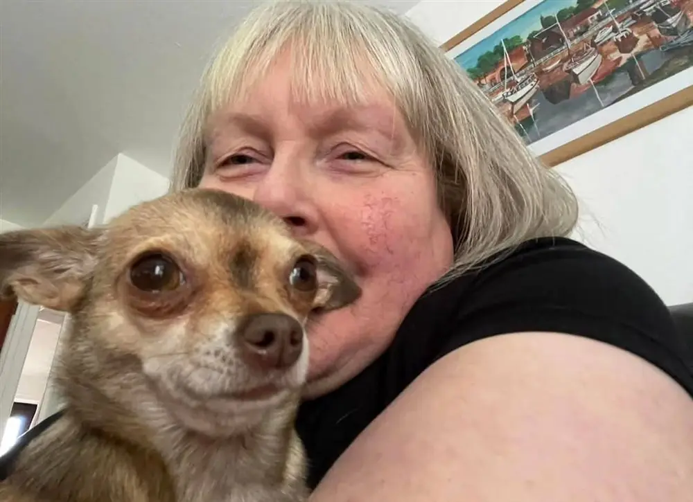 Woman taking a selfie cheek to cheek with a fawn Chihuahua